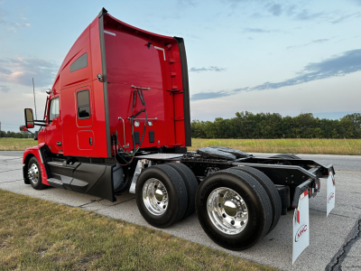 Kenworth T680 semi truck cab and chassis showing red sleeper cab and dual rear axles with chrome wheels.