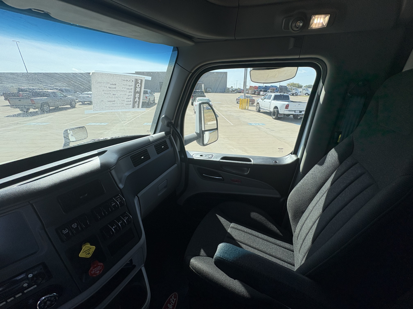 Truck cab interior of a 2024 Peterbilt 579, driver seat visible, dashboard with controls, side window, rearview mirror.