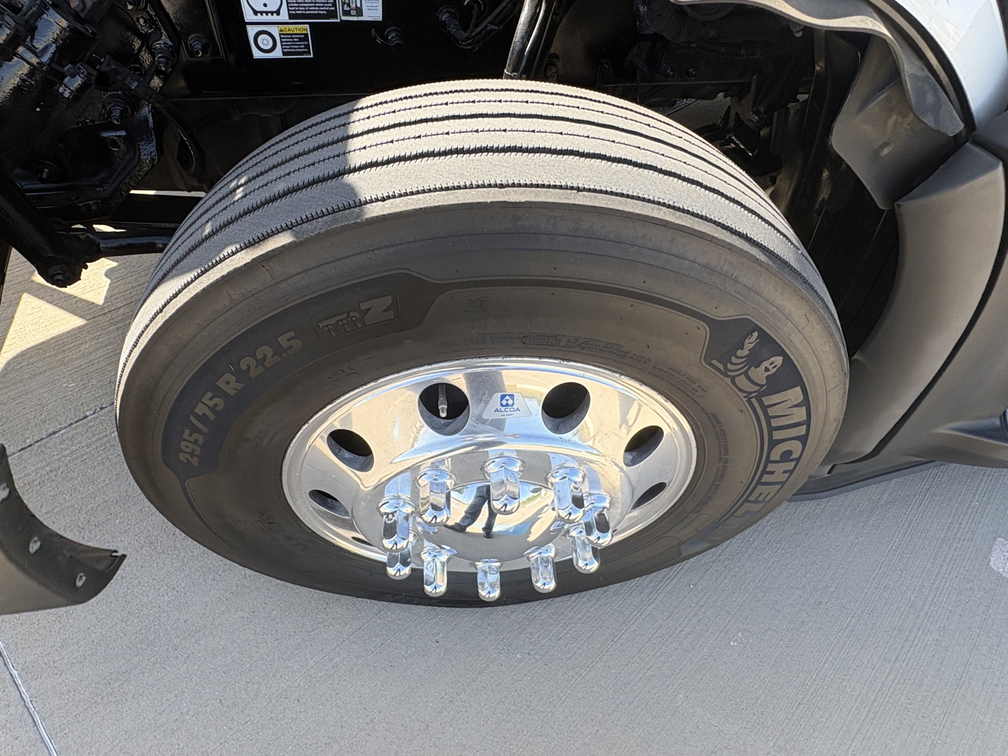Peterbilt 579 front wheel showing Michelin tire and chrome lug nuts, wheel rim, and fender area