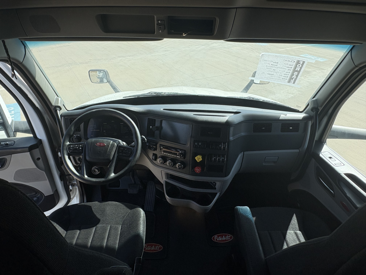Peterbilt 579 truck cab interior showing steering wheel, dashboard, and driver seat area with digital gauges and control panels.