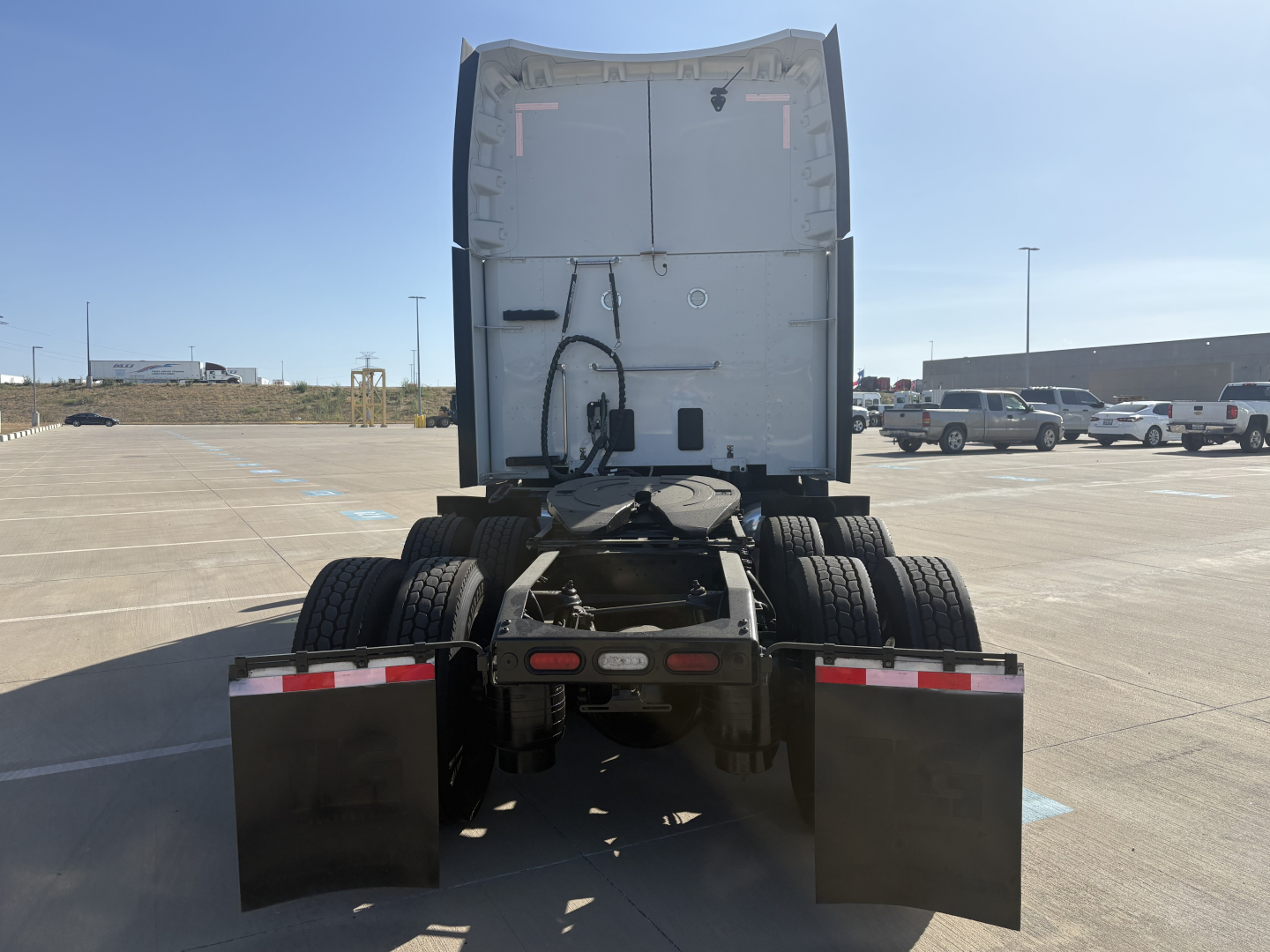 Peterbilt 579 rear view showing tractor and dual rear axles with mudflaps and chassis details, skyline of parking lot. Visible text: VIN 1XPBDP9X4RD602328 on listing context not on image.
