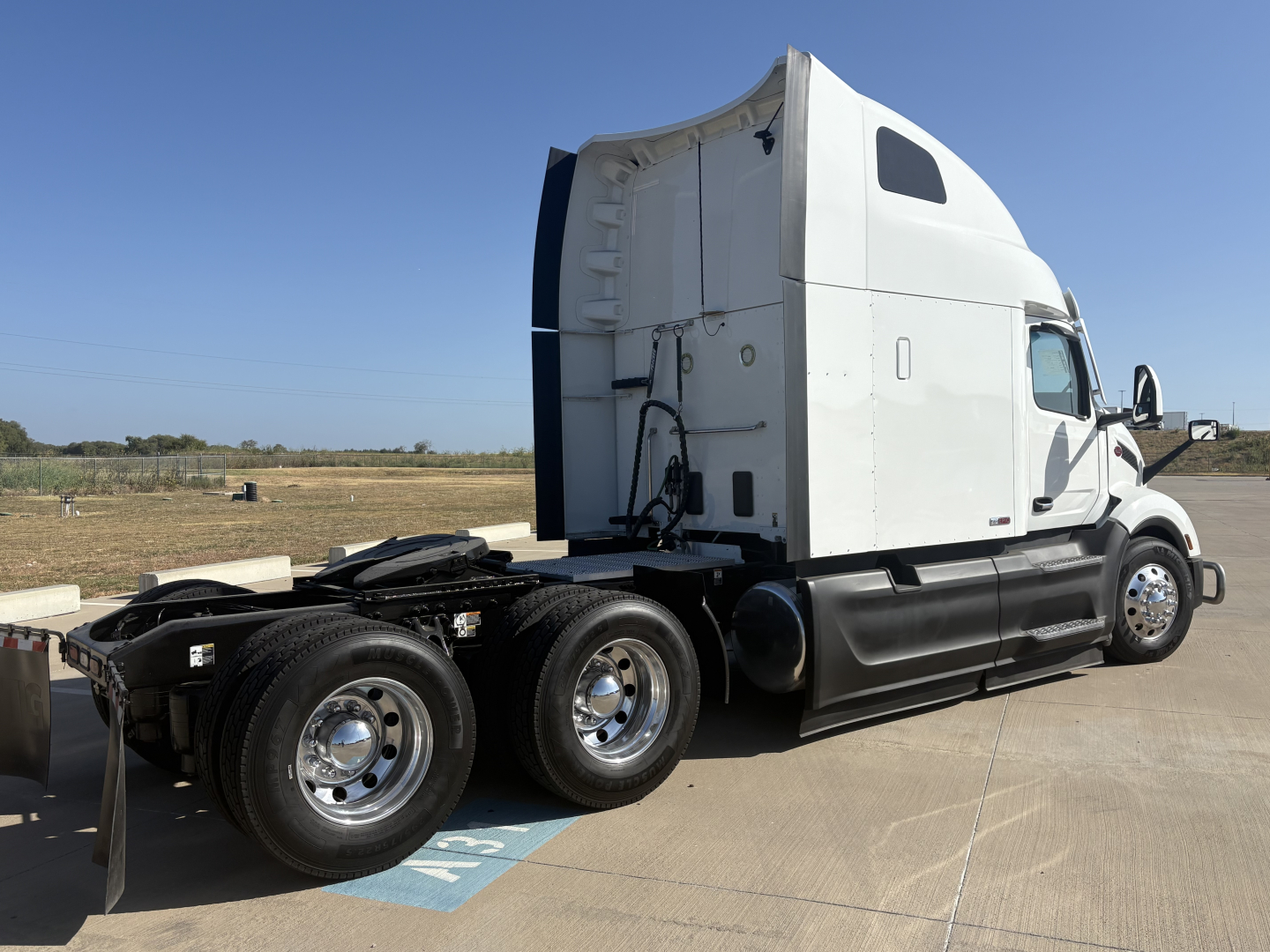 Peterbilt 579 sleeper cab tractor seen from the side, rear wheels and hitch exposed.