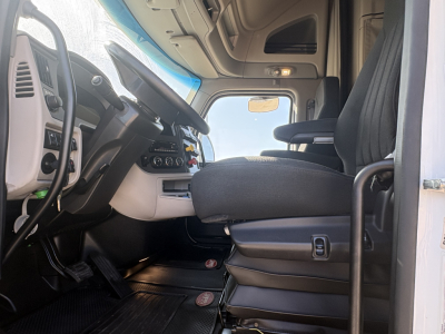 Peterbilt 579 truck cab interior view from the driver seat showing steering wheel, dashboard controls, and seating area.