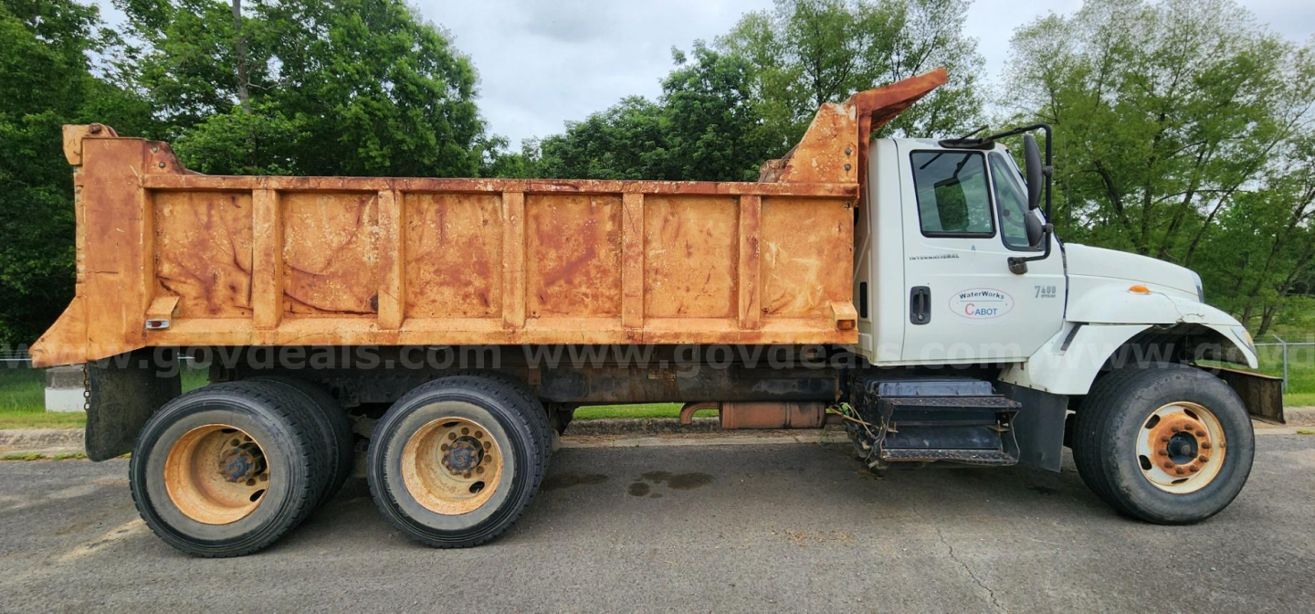 Dump truck in-service showing large orange dump bed and white cab with dual rear wheels.