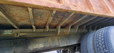Underbody view of a dump truck chassis showing the frame rails and wheel area.