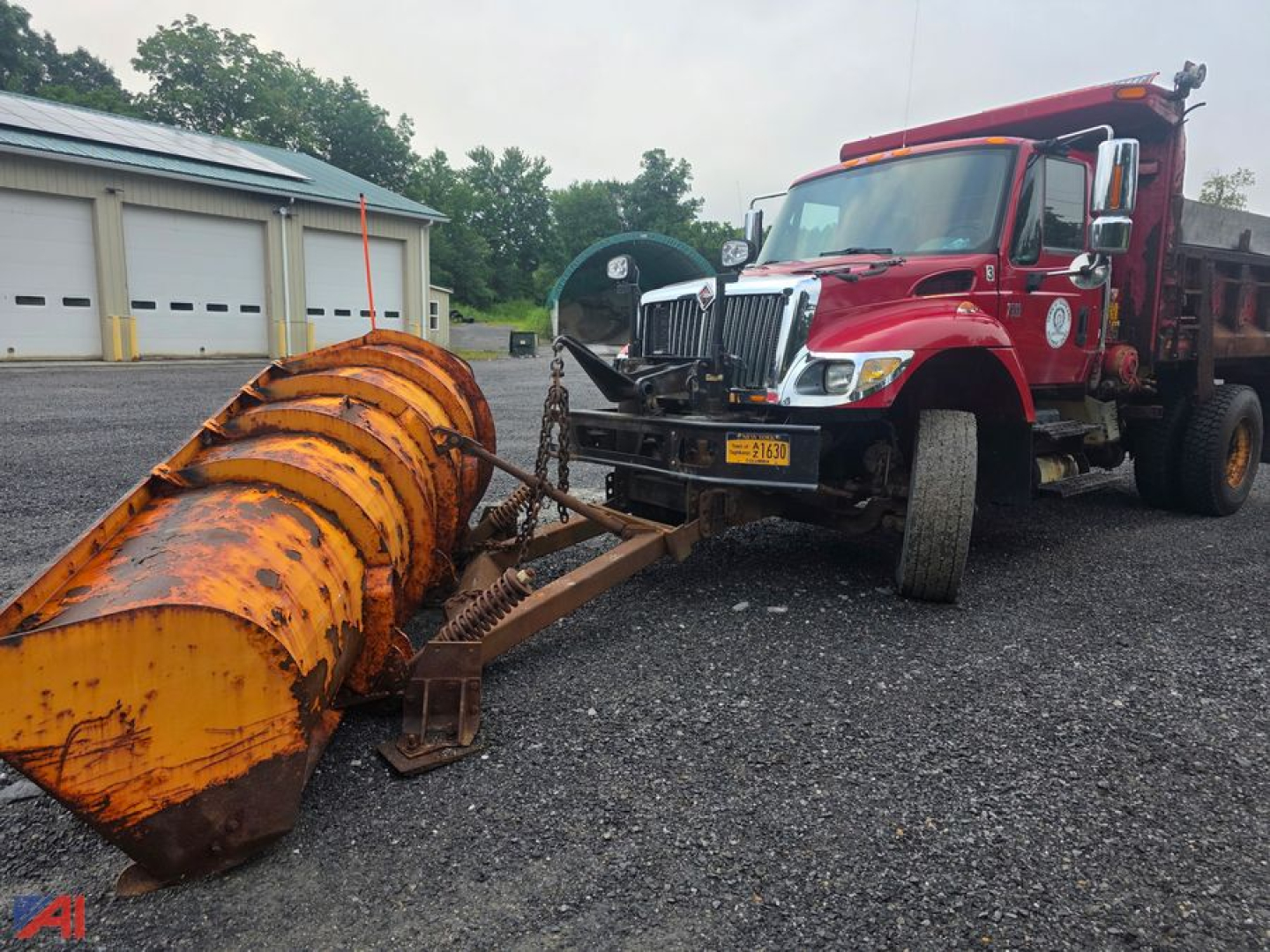 Dump truck in-service with an orange snow plow attachment at the front, red cab, International WorkStar 7500, chrome grille, diesel engine