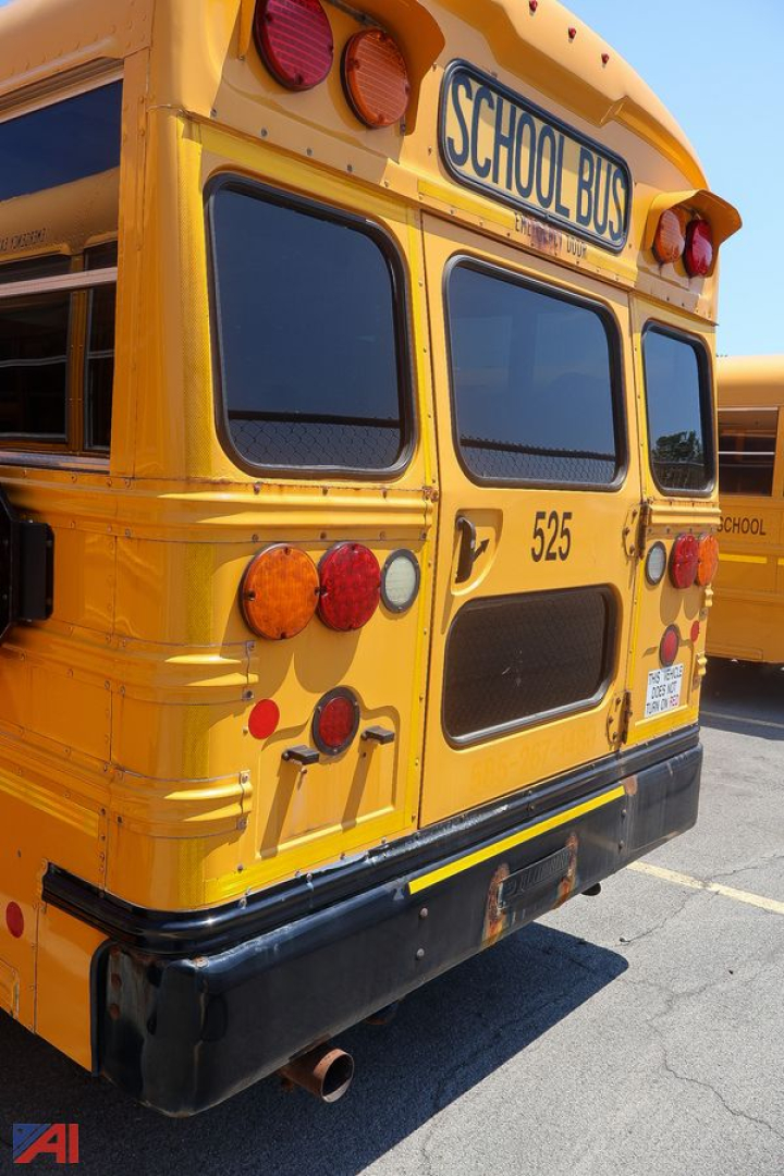 Rear view of a 2017 Blue Bird Vision mid-size school bus showing yellow body, back doors, tail lights, rear bumper, exhaust, and School Bus sign.