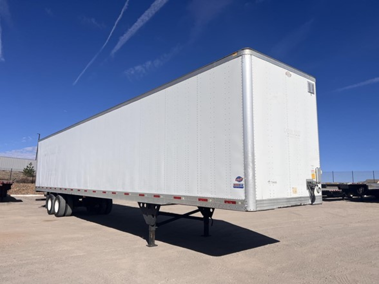 Trailer side view of a 2012 utility air ride dry van with white exterior and rear doors, stationary on a paved lot.