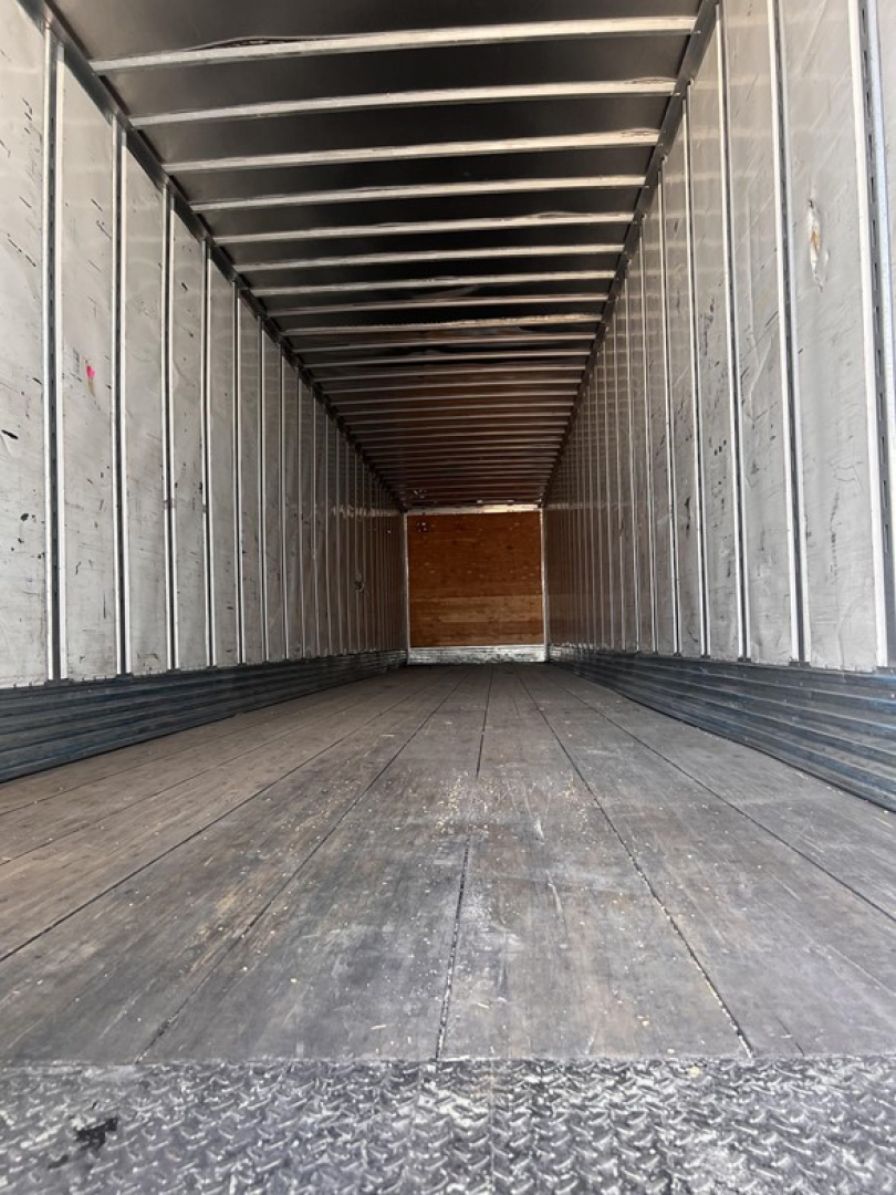 Interior of a 2012 Utility air ride dry van trailer with metal side walls and wooden floor, long empty cargo space looking toward the rear door.