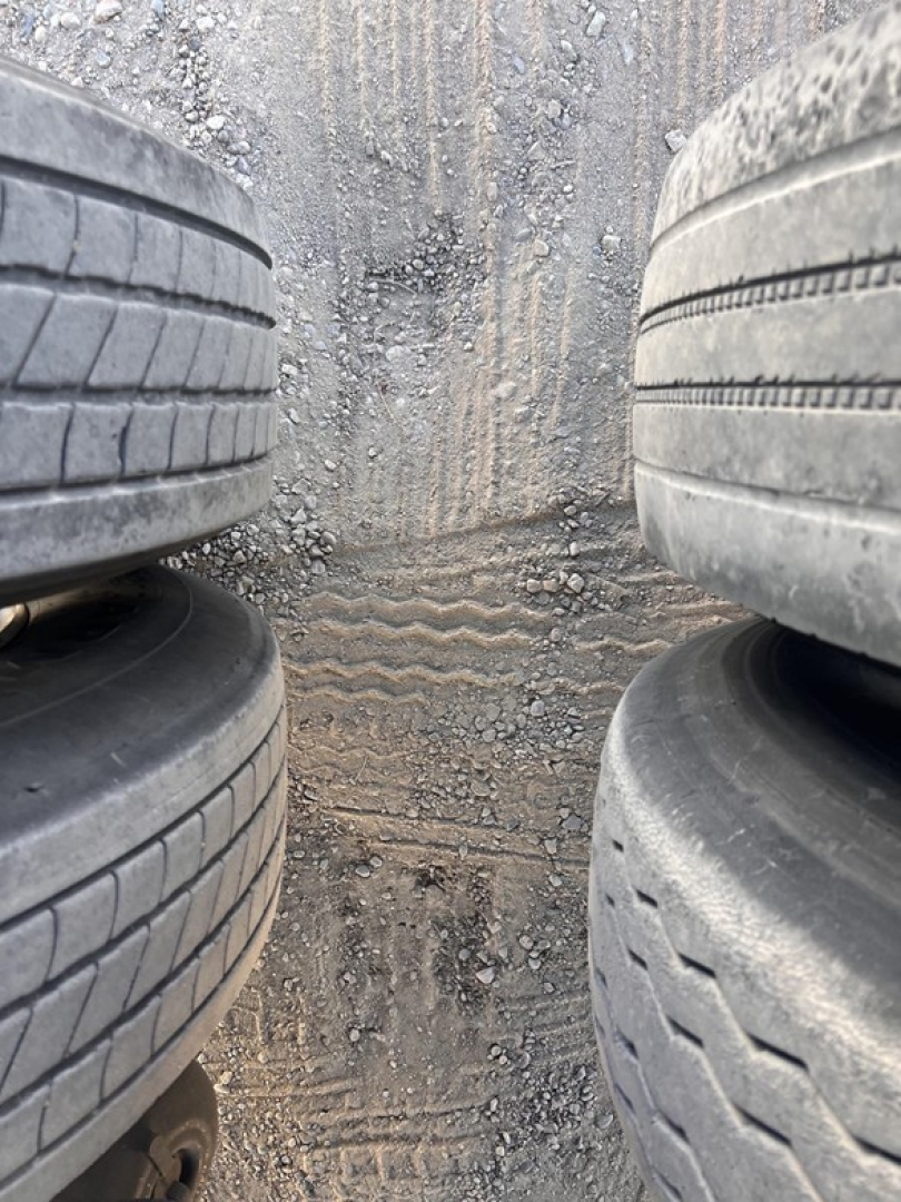 Trailer: dual stack of worn tires in a narrow space showing tread patterns and dirt. Center ground with marks.
