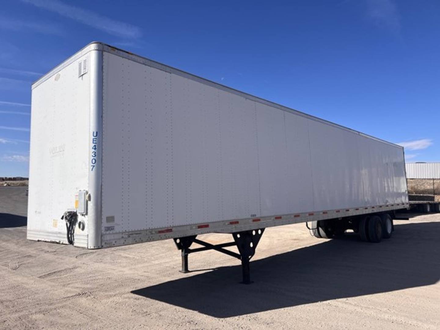 Utility dry van trailer in a side view showing a white exterior and support legs in front, no visible branding text readable.