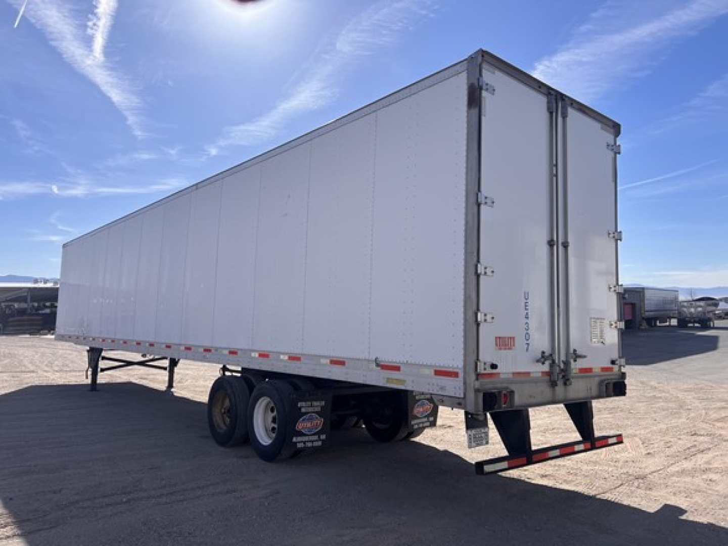 Trailer side and rear showing Utility air ride dry van with white panel and dual rear doors.