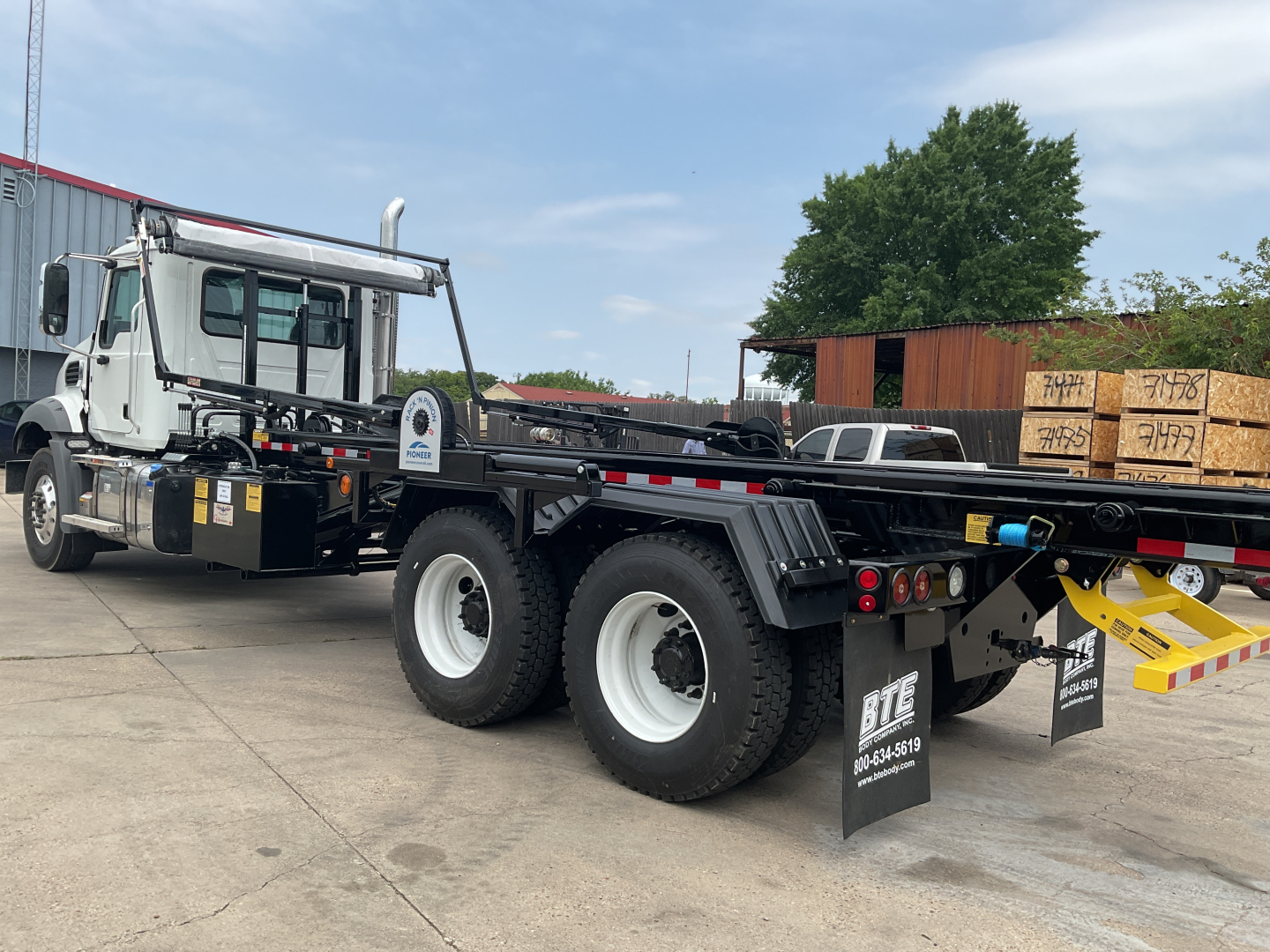 Mack GR64B rolloff truck with flatbed and dual rear axles, front cab, and loading ramp in layout.