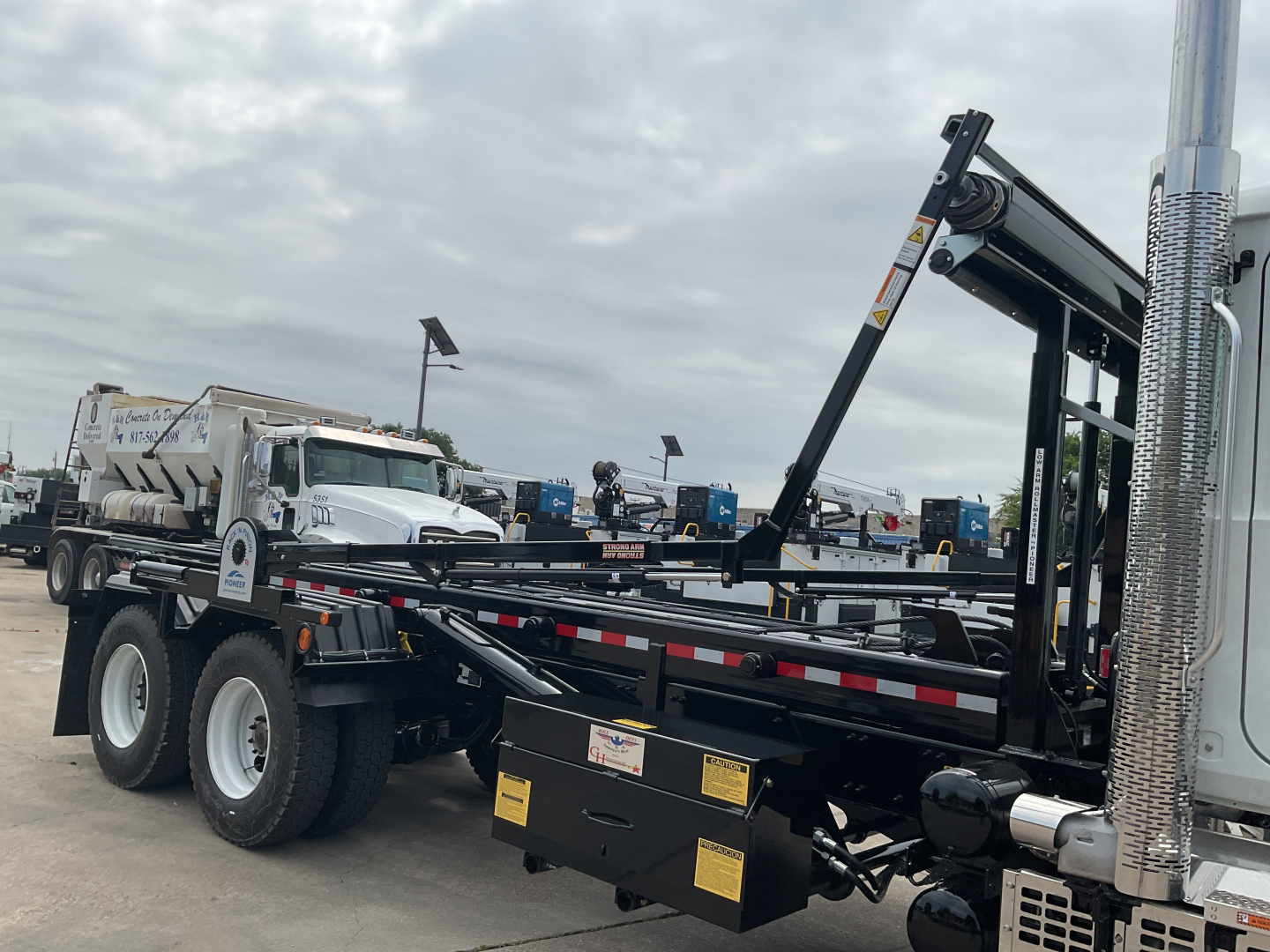Mack GR64B rolloff truck showing crane/tipping mechanism and chassis with dual rear axles.