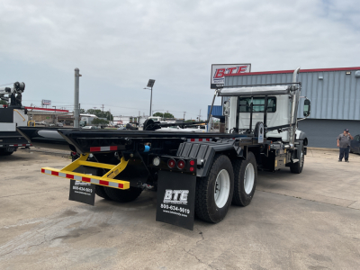 Mack GR64B roll-off truck rear view showing dual rear axles and rear bumper with BTE branding and contact numbers.