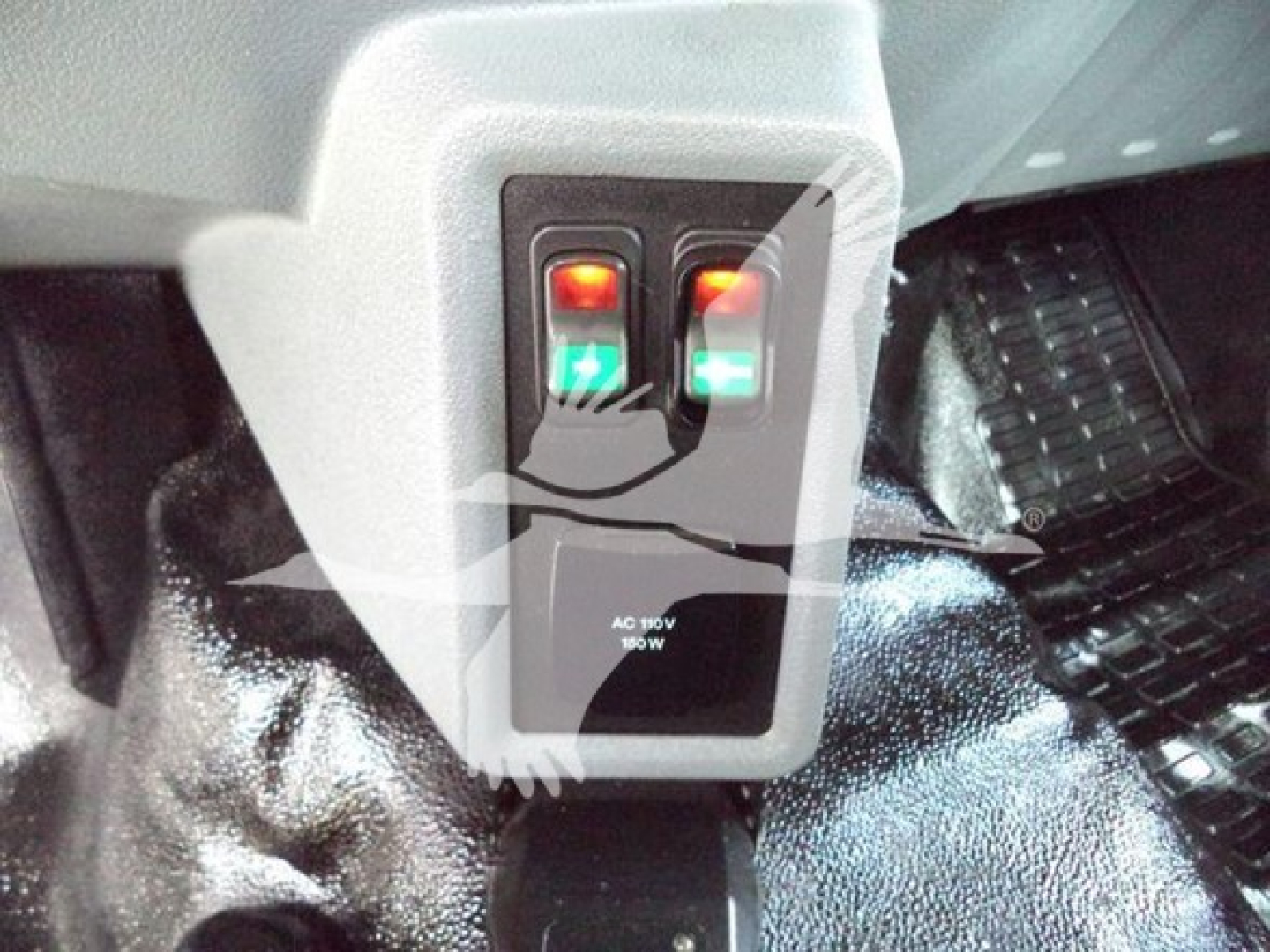 Ford F-750 bucket truck interior pedal area with two illuminated switches and a small panel labeled AC 180V 80W.