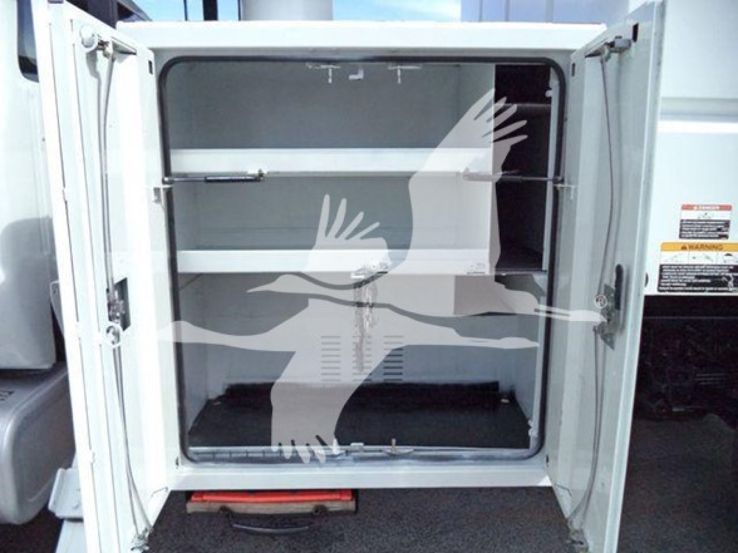 Ford F750 bucket truck rear cargo area with empty storage compartments and doors open.