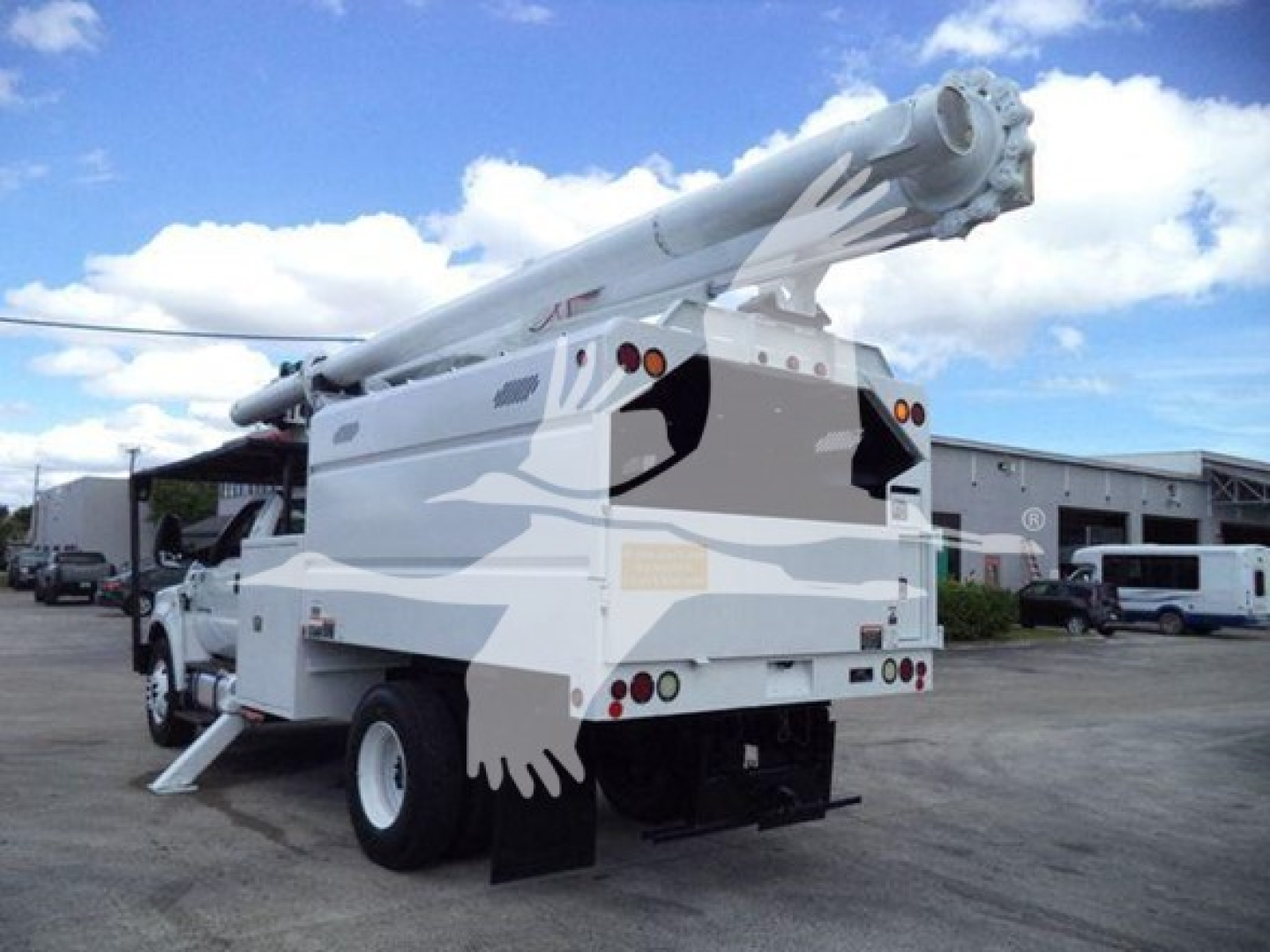 Ford F-750 bucket truck rear view with hydraulic boom folded overhead and stabilizer legs deployed.