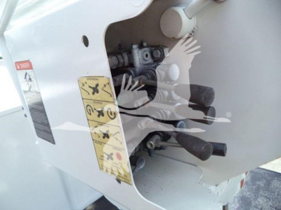 Ford F-Series bucket truck front side panel with control levers and warning decals visible.
