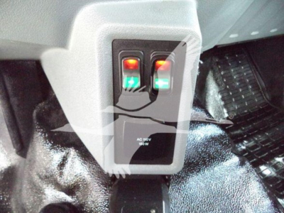 Ford F-750 bucket truck interior pedal area with two illuminated switches and a small panel labeled AC 180V 80W.