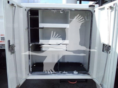 Truck storage compartment with shelves inside, doors open, white interior, utility vehicle.