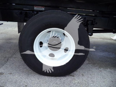 Truck wheel and tire showing white steel rim and black tire under Ford F750 bucket truck.