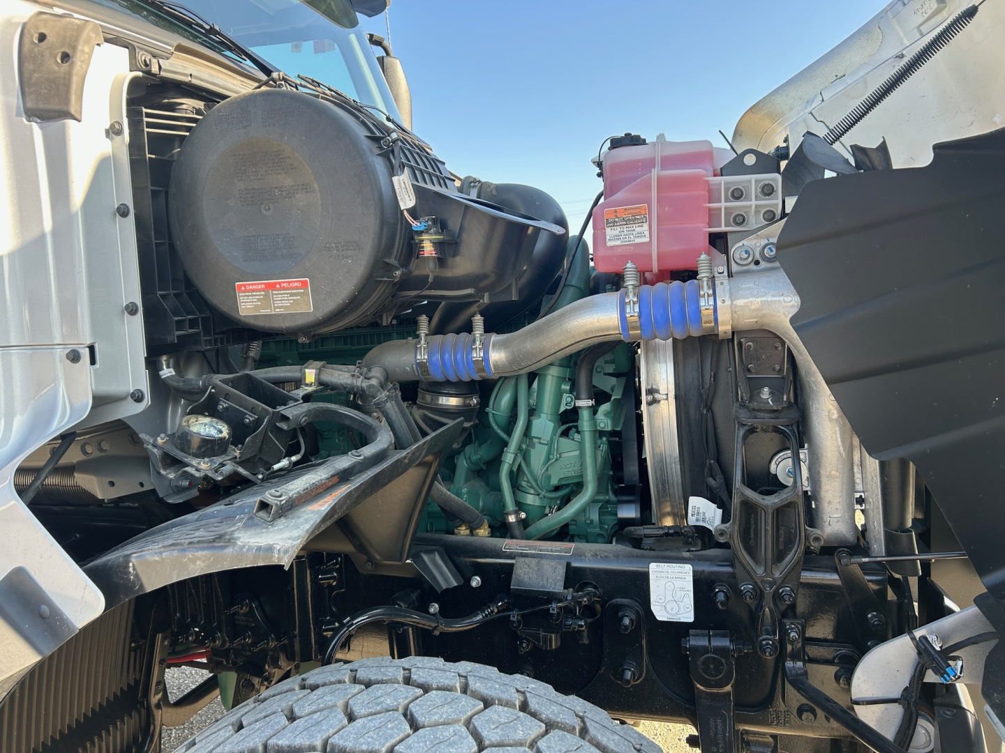 Volvo VHD84F300 engine bay showing diesel engine with green block, air intake, radiator, coolant reservoir, hoses, and construction truck components.