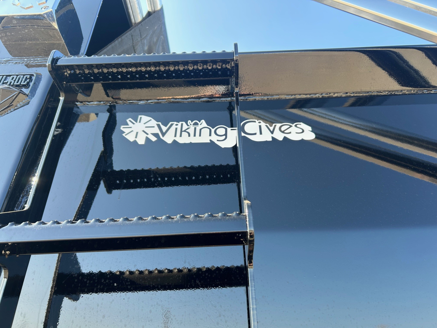 View of a Volvo VHD84F300 dump truck showing a Viking-Cives logo on the glossy black surface near a metal ladder/steps.