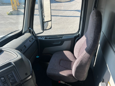 Truck cab interior front seat area of a Volvo VHD84F300. Visible steering area, dashboard, driver seat, side window, and mirror.