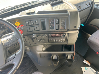 Dashboard of a Volvo VHD84F300 truck showing steering wheel, instrument cluster, climate controls, and gear selector with auxiliary cup holders.