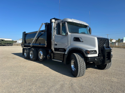 Volvo dump truck shown in side-front view with gray cab and black dump bed. Visible text on grille and windows not legible.
