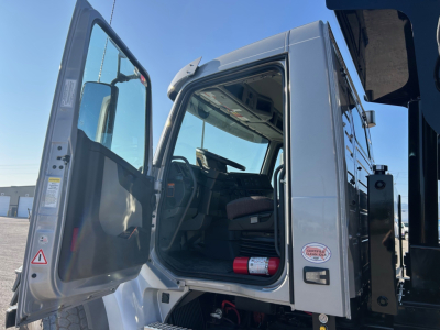 Volvo VHD84F300 dump truck cab interior with open door showing steering wheel and dashboard; door frame and exterior chrome accents visible.