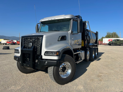 Volvo VHD84F300 dump truck in a parking lot, front-left view showing grille, large bumper, dual rear axles, and dump bed.