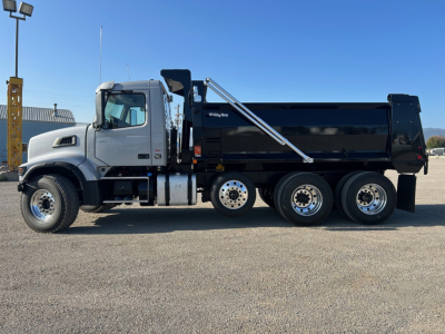 Dump truck side view showing Volvo VHD84F300 chassis with black dump body and chrome fuel tanks. No text clearly visible on body in this image.