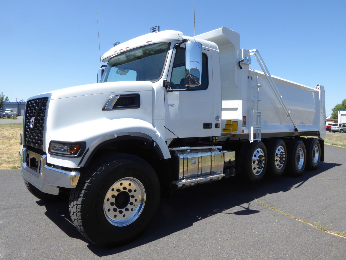 Dump truck showing Volvo VHD104F300 with three-axle configuration and white cab and dump body.