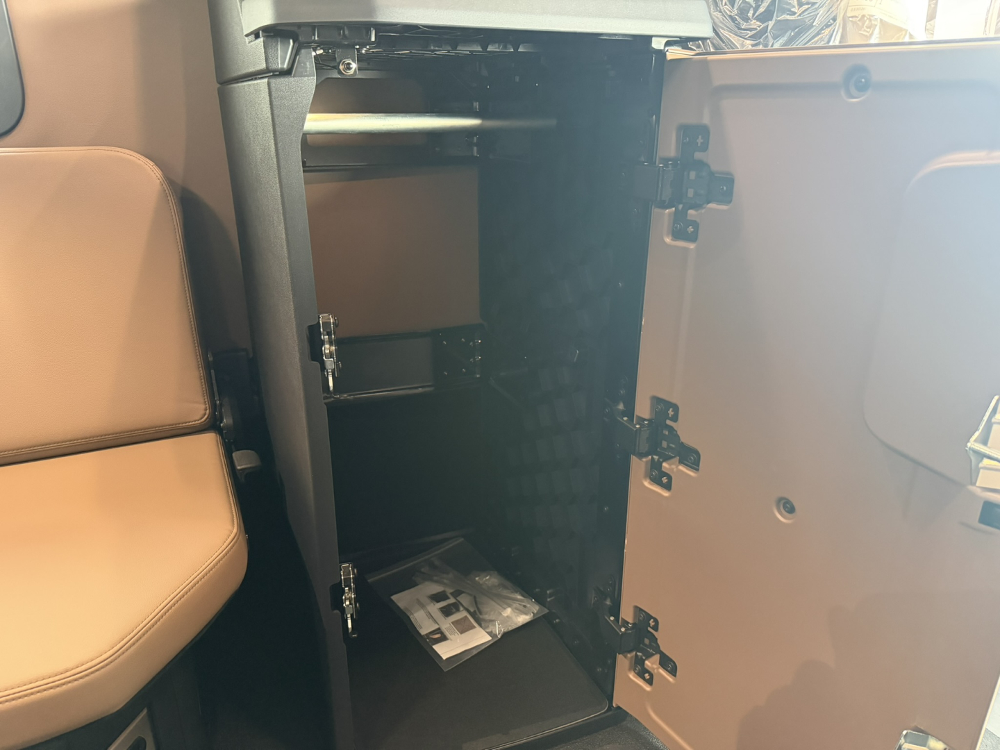 Open cabinet in a Mack truck cab showing interior shelves and a small packet on the bottom shelf.