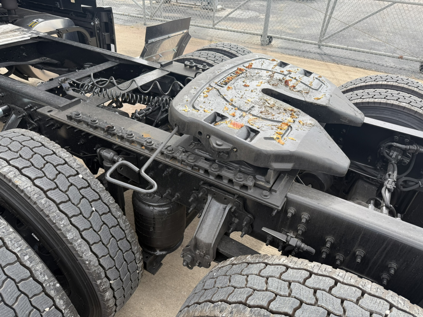 Mack PR64T76H tractor-trailer chassis showing dual rear axles and fifth wheel area with oily grime and spare parts; view of cabless tractor frame.