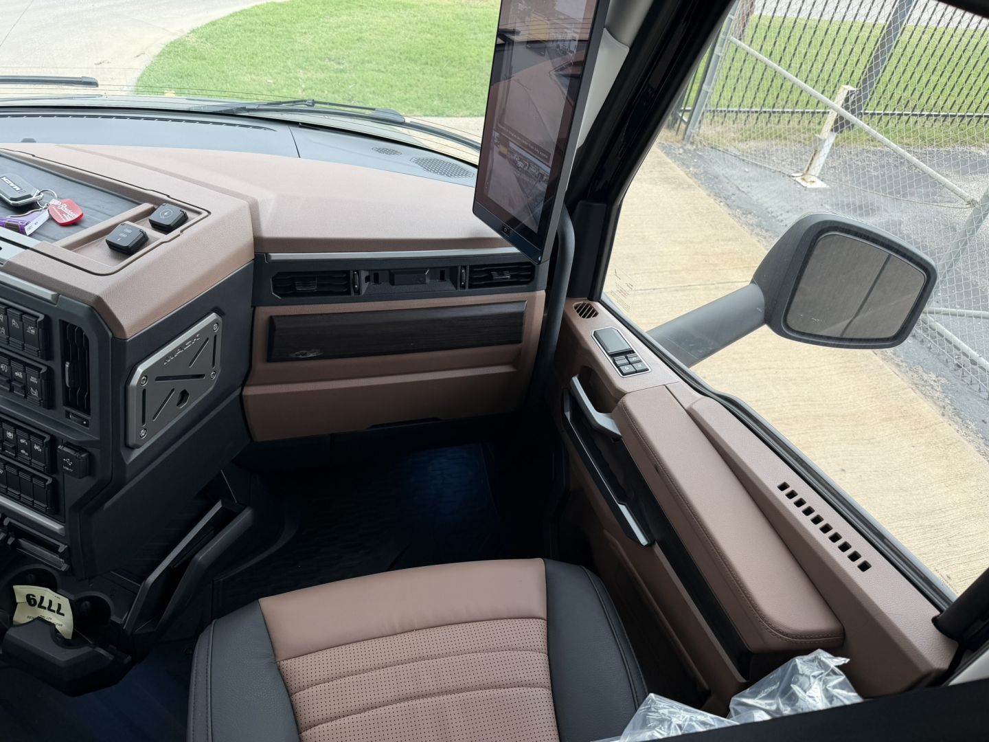 Mack PR64T76H truck interior cab view showing dashboard, steering wheel, driver seat, and brown trim panels.