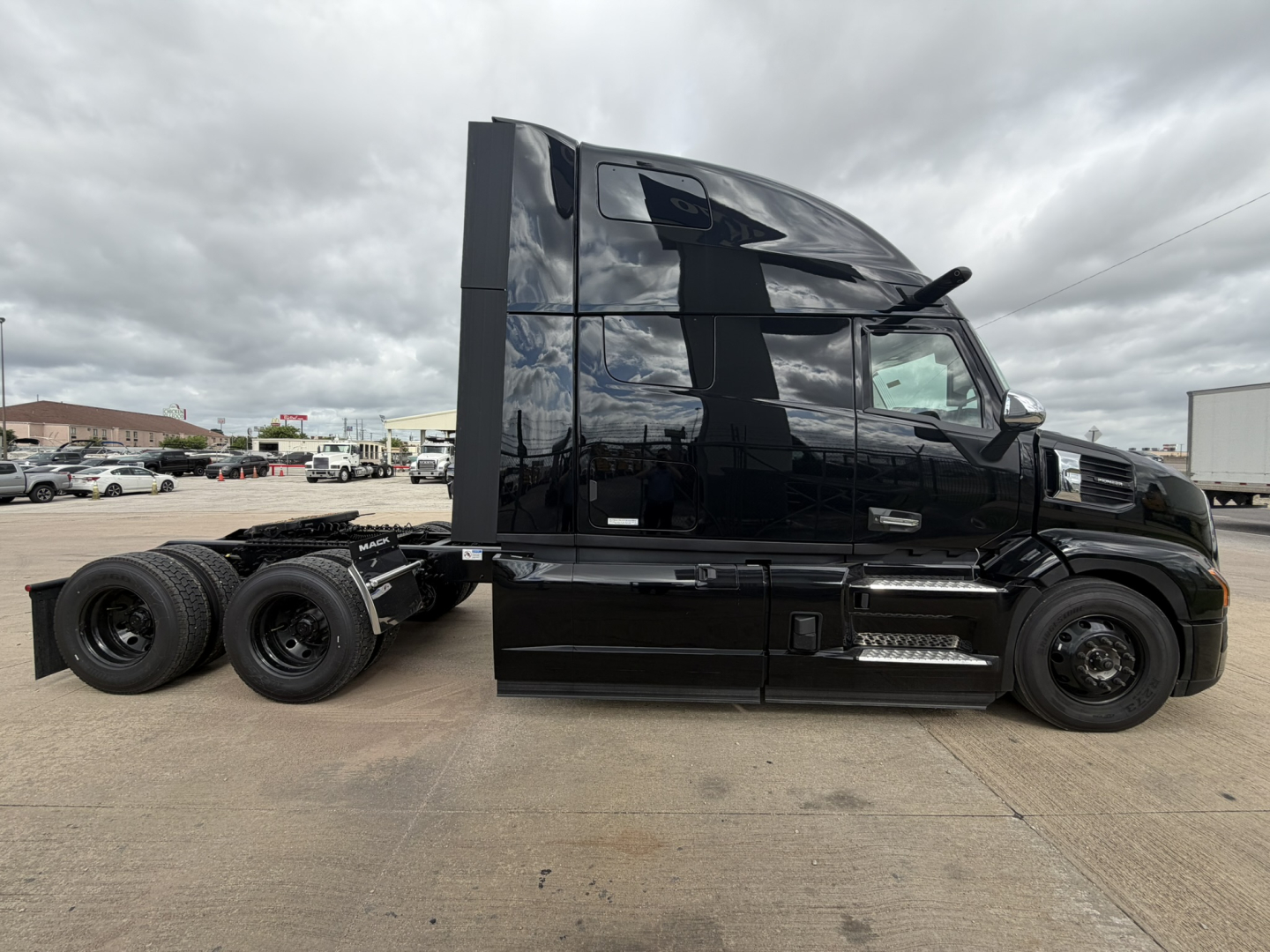 Mack PR64T76H tractor unit side view with sleeper cab, black exterior, dual rear axles, chrome steps, and large aerodynamic cab fairing.