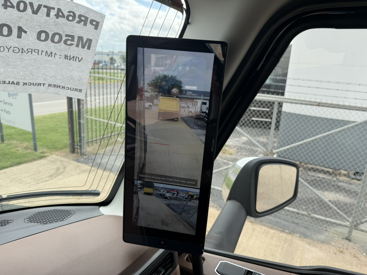 Mack PR64T76H truck interior showing a vertical tablet display mounted near the windshield with outside lot view and gate.
