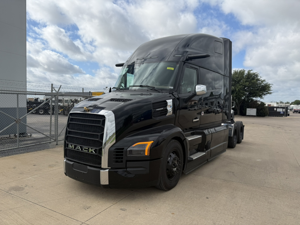 Mack PR64T76H tractor-trailer truck in black, front three-quarter view, with sleeper cab, chrome grille, and side mirrors.