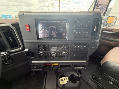 Dashboard panel of a Mack truck with a touchscreen display and various control panels. Visible text includes switches and gauges but no legible model-specific labels.