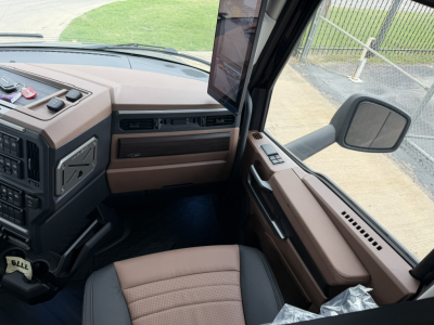 Mack PR64T76H truck interior cab view showing dashboard, steering wheel, driver seat, and brown trim panels.