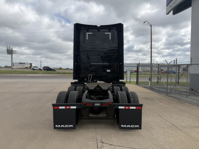Mack PR64T76H truck rear view showing fifth wheel and dual rear tires with black cab portion, yard fence, and cloudy sky.