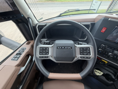 Mack PR64T76H steering wheel and dashboard inside cab showing Mack logo on center, digital gauges, control buttons on both sides of wheel.