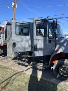 Cabin side view of 2012 International DuraStar 4300 Crew Cab Dump Truck with grey exterior and step ladder, visible side mirrors and doors.