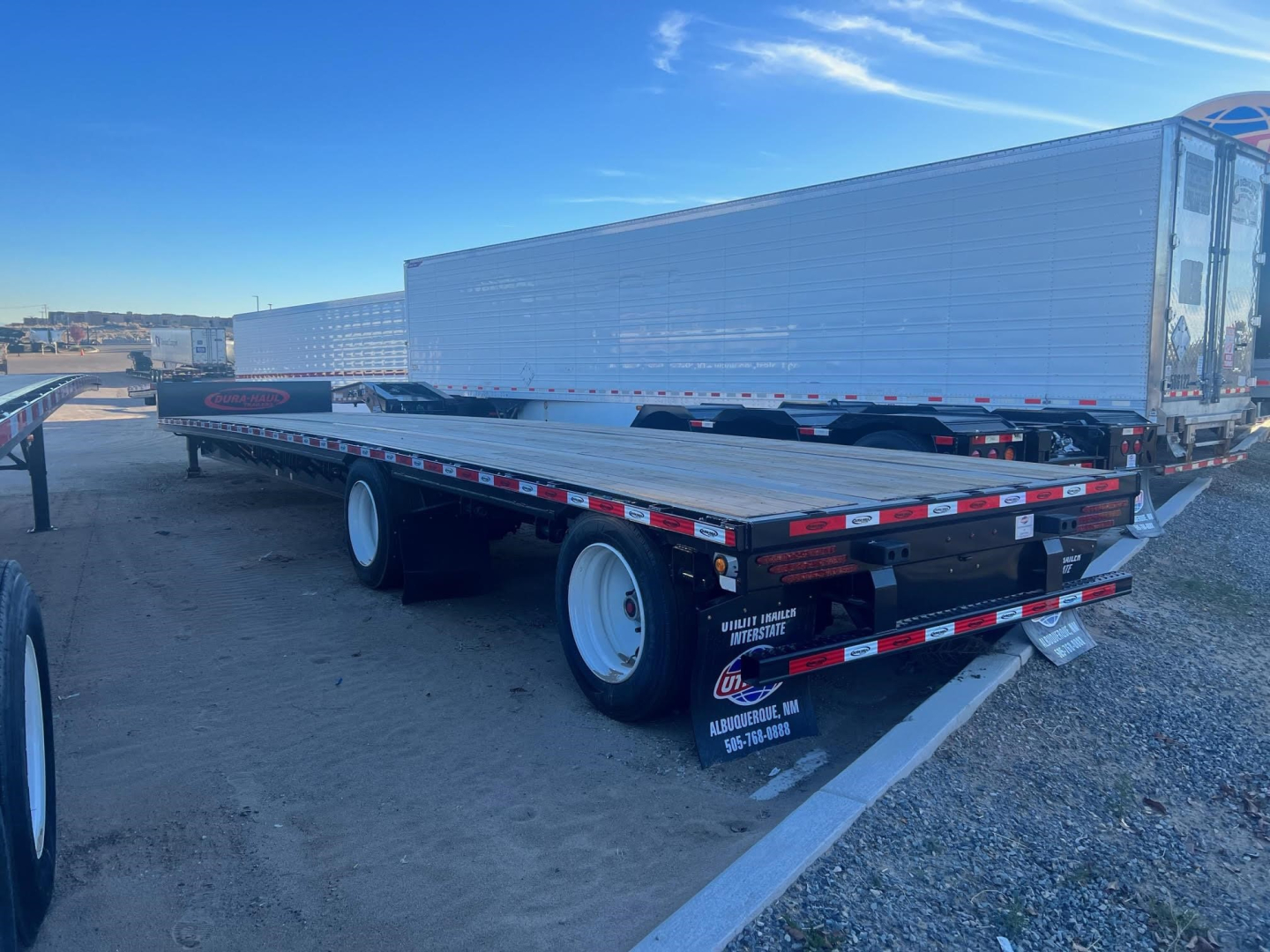 Trailer showing flatbed with steel drop deck and white wheels, NE10258 stock trailer lot.