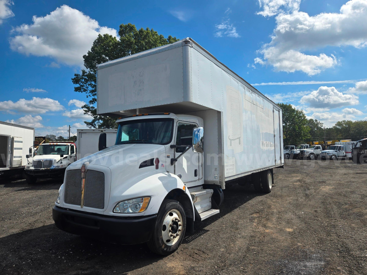 Kenworth box truck 2018, side view showing cargo box with cab in foreground and clear sky.
