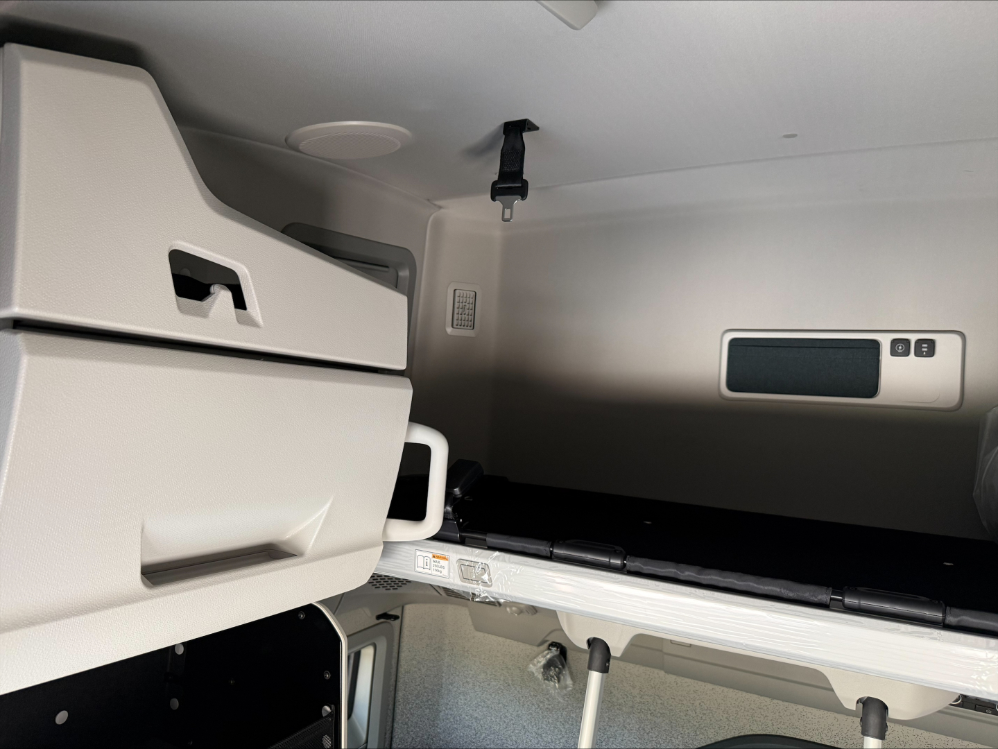 Volvo VNL sleeper cab interior showing bunk area and storage cabinet, with control panel and seat in view.