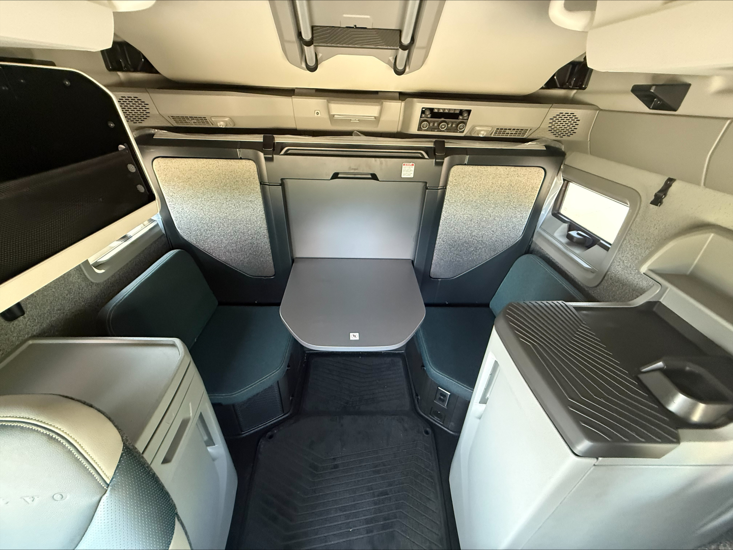 Volvo VNL64T860 cab interior showing sleeper area with table, seating, and overhead controls.